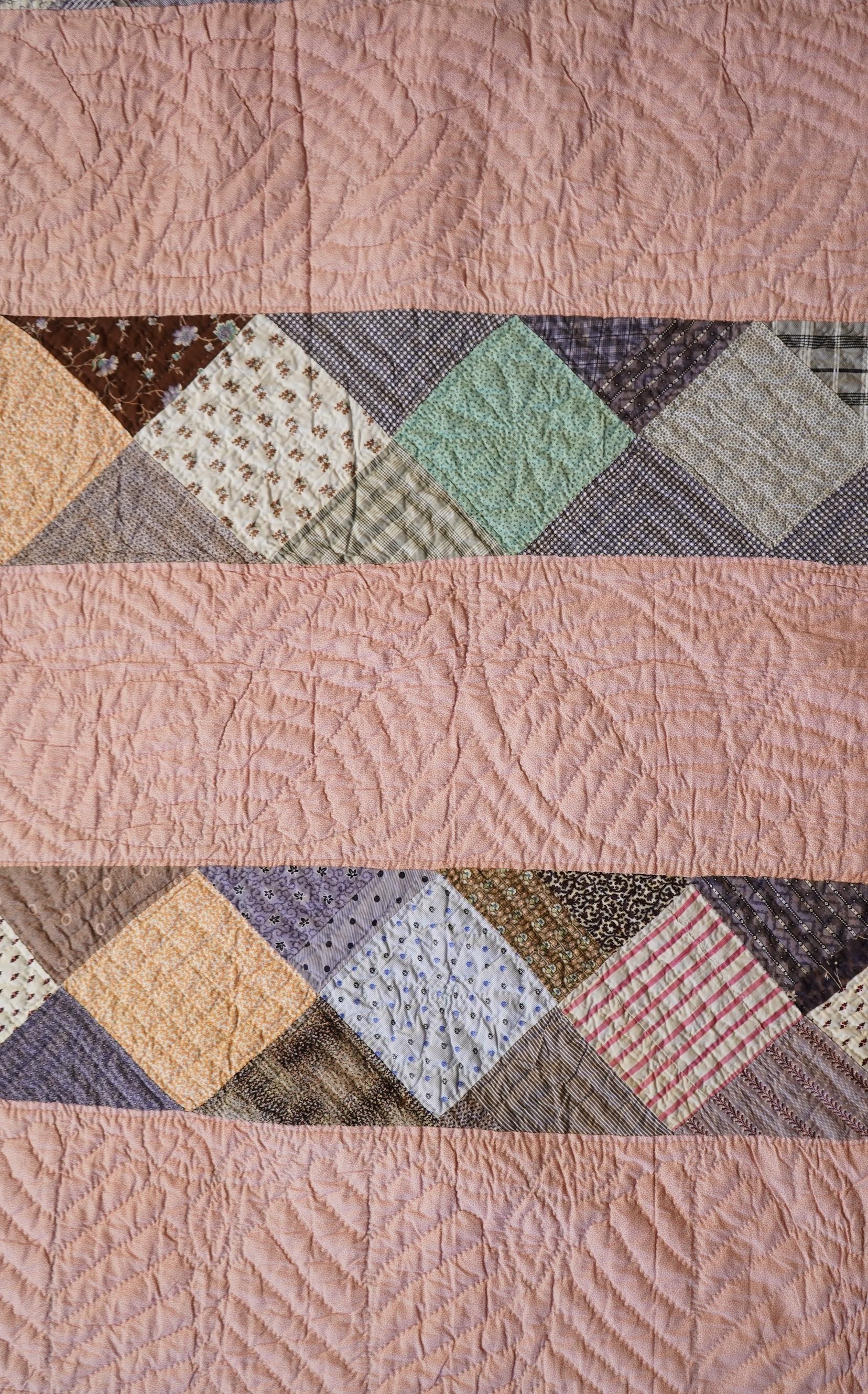 A late 19th century English, possibly ‘North Country’ cotton, hand quilted bed cover. Worked in stripes, with alternate patch worked stripes of differing colour fabrics. Made from fashionable cotton fabrics of the era. R